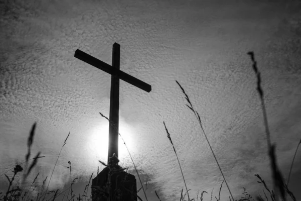 Black and white photo of a cross against the sky in small clouds — ストック写真