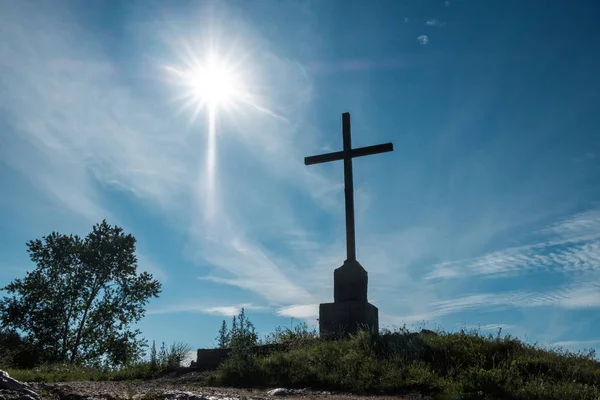 Cross on a mountain against a blue sky and bright sun — ストック写真