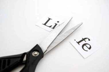 Beyaz arka planda, hayat makasla kesilir. Kâğıttaki yazı kesilmiş.