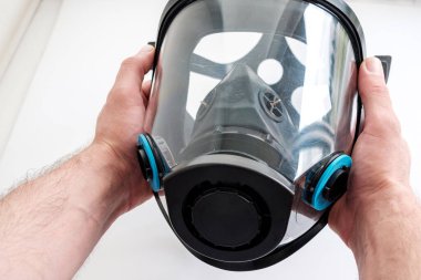 Gaz ve tozdan korunmak için iki elle bir gaz maskesi tutuyorlar. Işıkta görünen çip ve çatlakları kontrol et