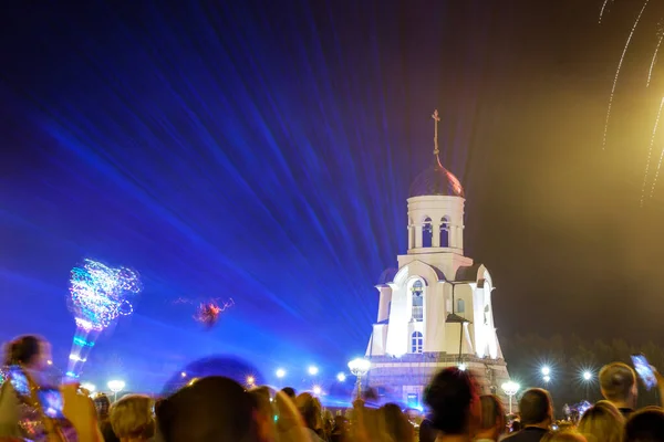 flashes of lighting in blue against the background of a chapel in the city center. The crowd looks up during the holiday. Kamensk-Uralsky Russia city day