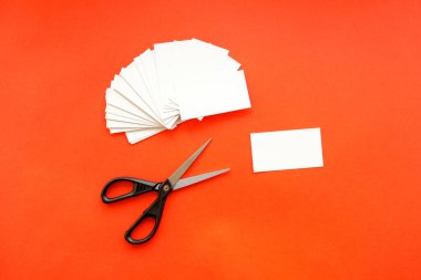 Kırmızı arka planda bir sürü kartvizit ve makas var. gereksiz kartları yok et