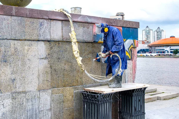 Rusya, Yekaterinburg, 14 Ağustos 2019. Bir kamu hizmetleri çalışanı duvardaki grafitiyi suyla kaldırıyor. Duvardaki boyayı söküyor.