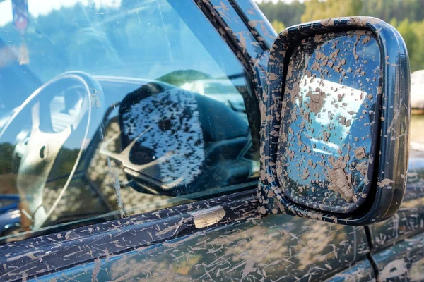 dirt on the side mirror of an off-road car in the Parking lot. outside the car came from the forest traces of dirt