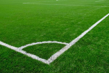 Yapay yeşil çimlerle kaplı bir futbol sahasında beyaz köşe işaretleri