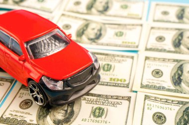 Kırmızı bir oyuncak araba bir banknotun üzerinde. araba satışı
