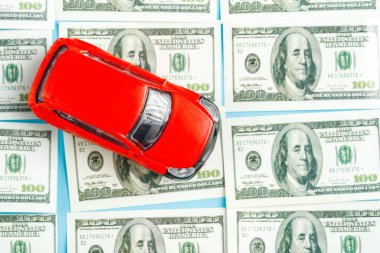 Dolar banknotları üzerinde kırmızı bir oyuncak arabanın üst görüntüsü. satıcı oyunu