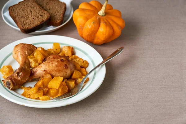 Baked chicken legs with pumpkin on a white plate