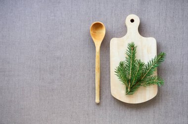 Kahverengi tekstil arka planında tahta kesme tahtası ve kaşık                                