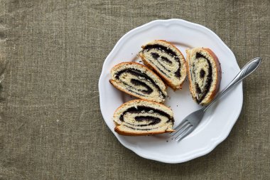 Beyaz bir tabakta haşhaş tohumlu rulo dilimleri.                               