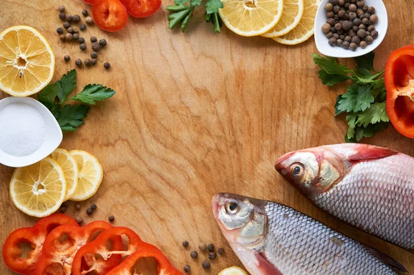 Raw roach fish with lemon and pepper on a wooden background