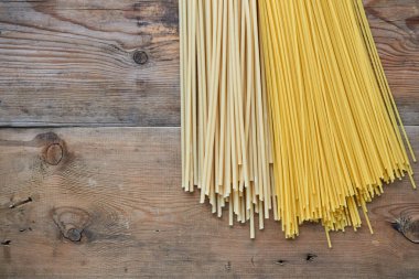 Different raw spaghetti on old wooden background                               