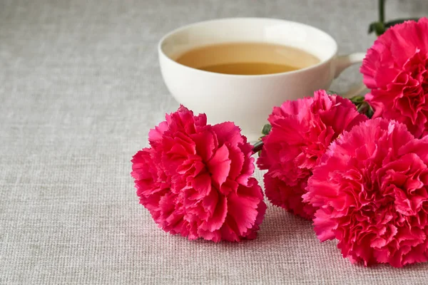 Strauß Rosa Nelken Mit Tee Auf Grauem Stoff Hintergrund — Stockfoto