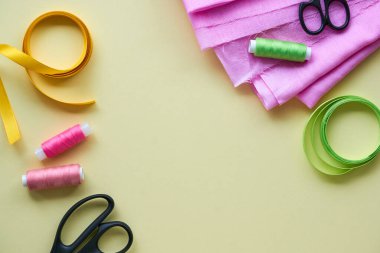 Açık arkaplanda dikiş aksesuarları olan pembe pamuk kumaş.                               