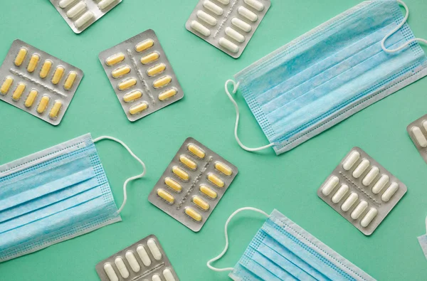 Renkli arka planda çeşitli haplar bulunan tıbbi maskeler.