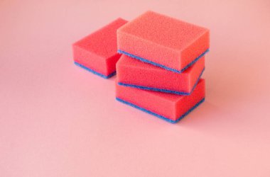 Renkli arka planda bulaşık yıkamak için pembe süngerler.