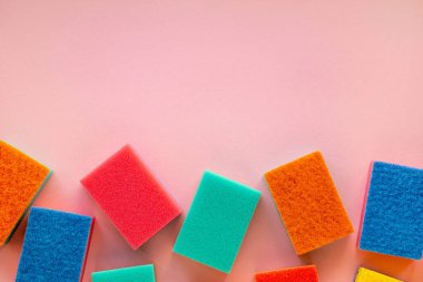 Pembe arka planda çok renkli temizleyici süngerler