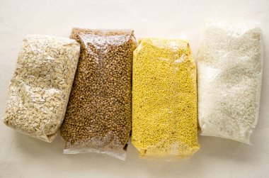 Hafif arka planda plastik ambalajda çeşitli çiğ tahıllar