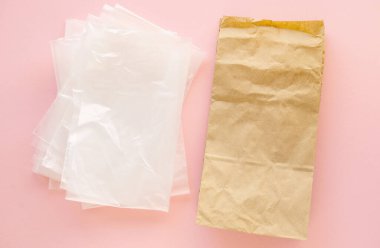 Pembe arka planda plastik torbalar ve kese kağıdı.