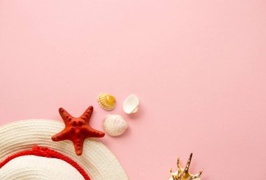 Pembe arka planda yaz şapkası ve deniz kabuğu düzeni
