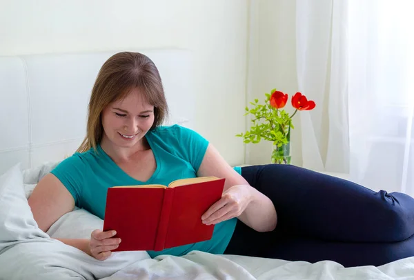 Радостная Молодая Женщина Лежит Кровати Читает Книгу — стоковое фото