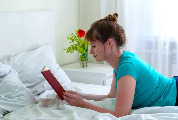 Улыбающаяся Молодая Женщина Лежит Дома Кровати Читает Книгу — стоковое фото