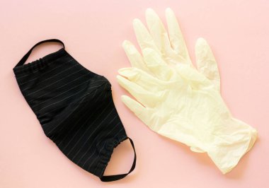 Pembe arka planda tıbbi eldivenli pamuk koruyucu maske.