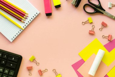 Pembe arka planda çeşitli okul ve ofis malzemeleri var.