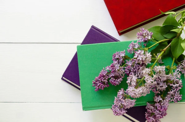 Hardback books with branch of lilac on a white background