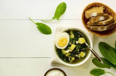 Beyaz zemin üzerinde yumurta ve patates olan yeşil bir çorba.