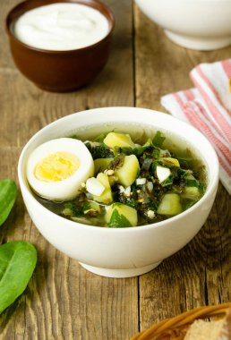 Yeşil sebze çorbası. Beyaz kâse içinde kuş yaprakları ve yumurtalar.