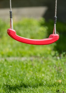 Yeşil çim üzerinde kırmızı bir salıncak detay