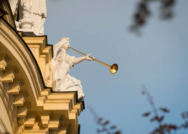 Figura de piedra con una trompeta dorada sentada en un edificio antiguo — Foto de Stock