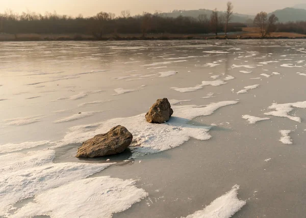 Pedras deitadas no rio congelado com manchas de neve clara — Fotografia de Stock