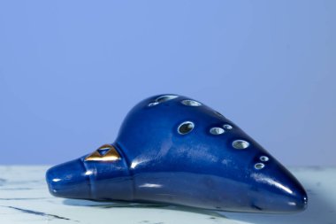 A blue ocarina in front of blue background clipart