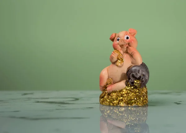 Figurine d'un petit cochon assis sur une pile d'or — Photo