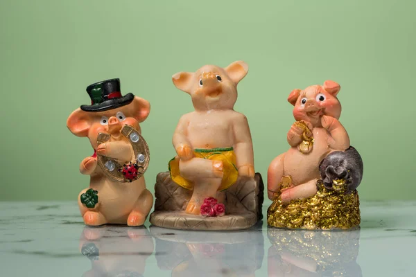 Drie beeldjes van New Year's piggies, groene achtergrond — Stockfoto