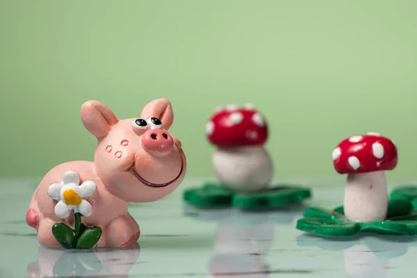 Figur eines kleinen Schweinchens mit einer weißen Blume und Pilzen — Stockfoto