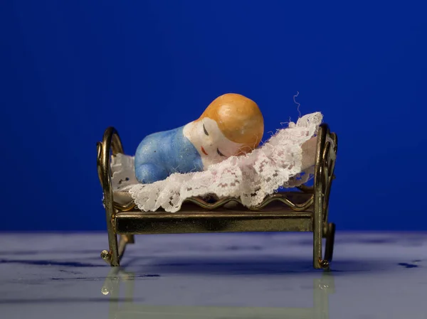 Primo piano di una piccola statuetta di un bambino che dorme a letto — Foto Stock