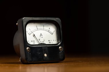 Ahşap bir masa üzerinde eski bir siyah analog amper metre
