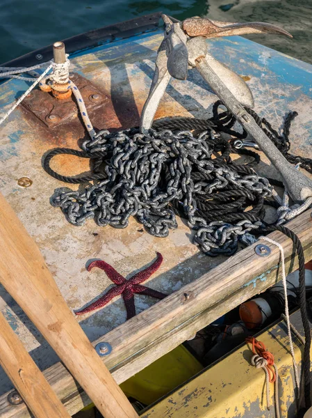 Closeup of an anchor, an iron chain and a starfish lying on a boat