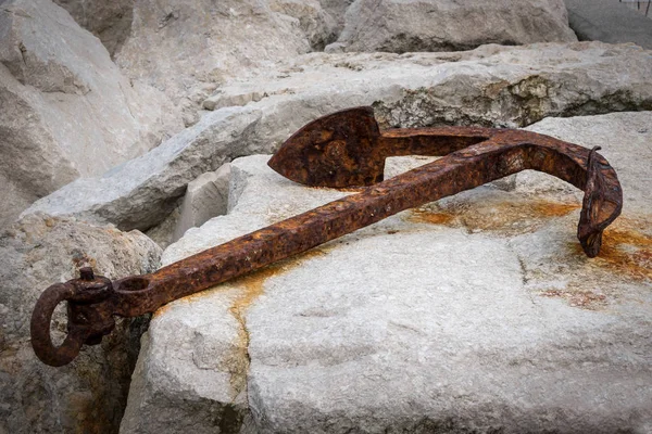 Μικρό σκουριασμένο άγκυρα που βρίσκεται στα βράχια σε ένα λιμάνι — Φωτογραφία Αρχείου