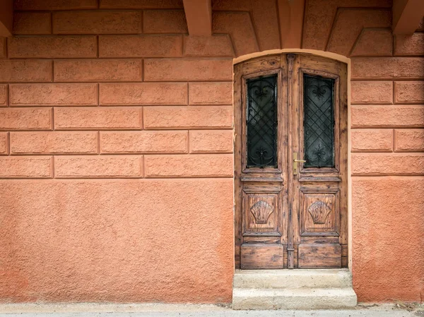Vecchia porta marrone intemperie in legno, parete arancione in Croazia — Foto Stock