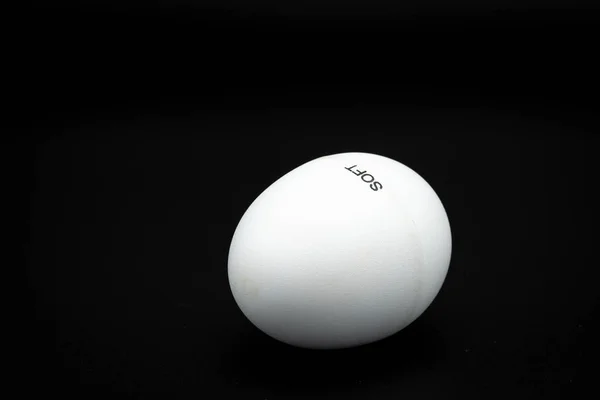 A white egg shaker lying on a black underground — Stock Photo, Image