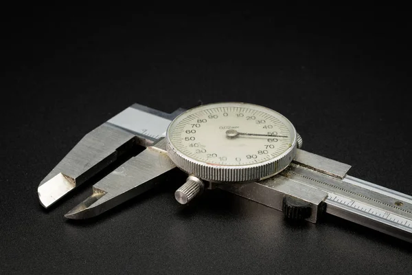 A dial caliper lying on a black background — 스톡 사진