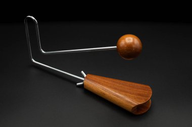 Bir vibraslap gümüşü, siyah yeraltı üzerinde kahverengi ahşap