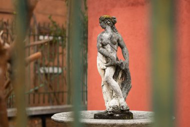Figure of a woman in front of red house in Venice