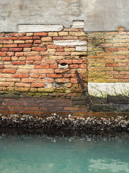 Un vecchio muro di mattoni vicino all'acqua a Venezia — Foto Stock