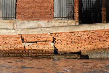 A broken brick wall in water in Murano