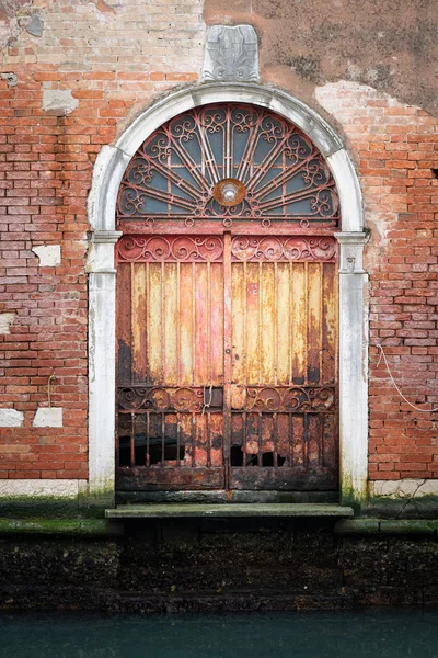 Ingresso in un vecchio muro di mattoni vicino all'acqua a Venezia — Foto Stock